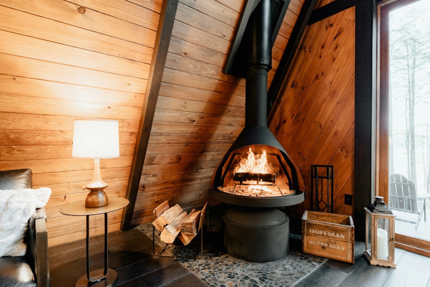 Freestanding fireplace glowing in a warm wood-panelled cabin interior